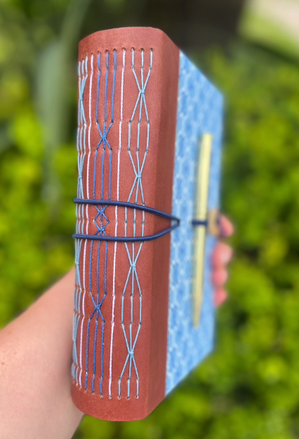 Lombada vinho de caderno azul com costura artesanal azul aparente